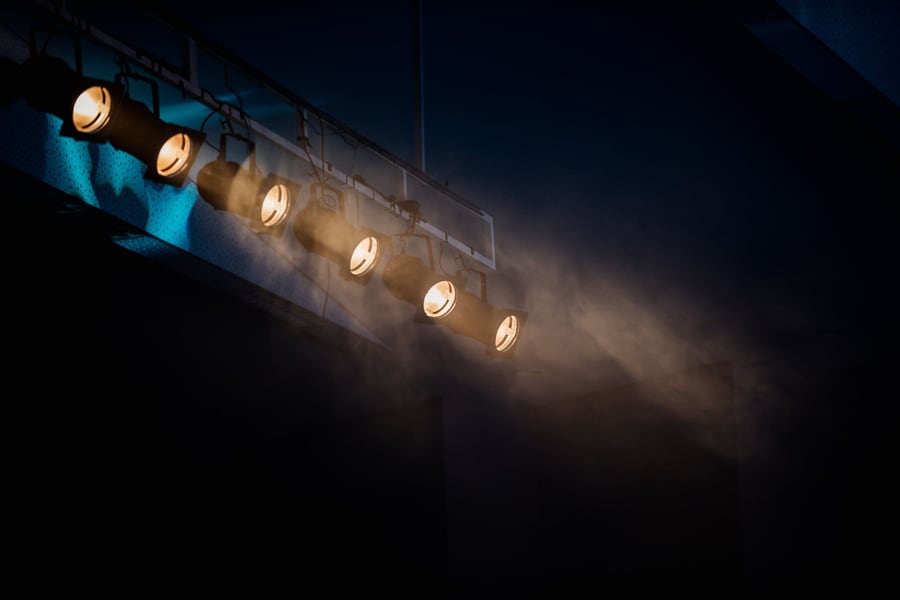 A row of warm par cans on a truss cutting through haze