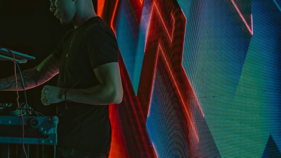 An operator at a control surface before a red and blue LED wall