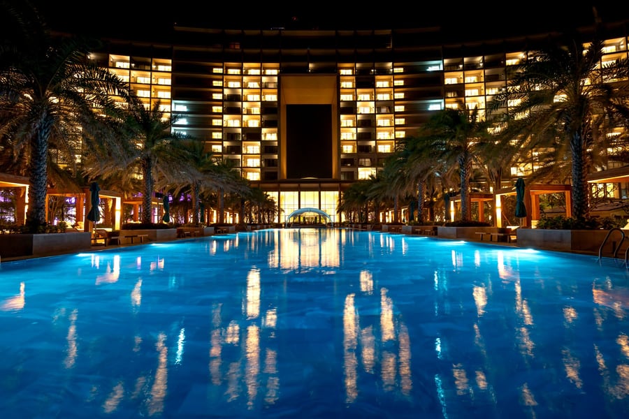 A resort facade lit at night, reflected in a pool