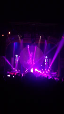Live — the circular screen over the band, beams cutting through haze