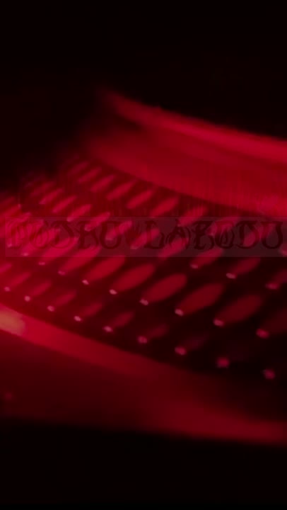 Rig hardware under red work light, rows of cells glowing in the dark