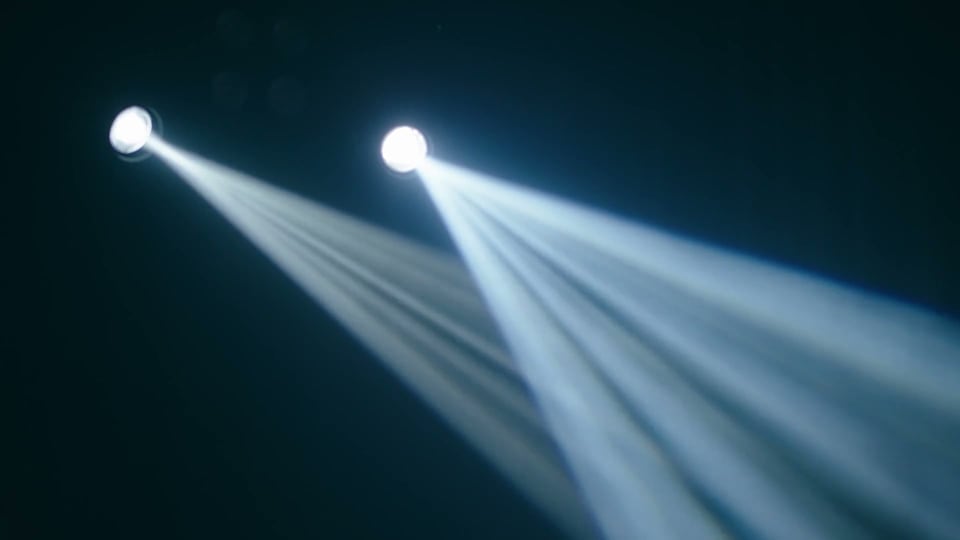 Two moving-head fixtures throwing hard beams through haze