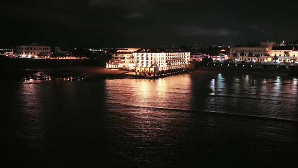 Aerial track along a lit waterfront building at night